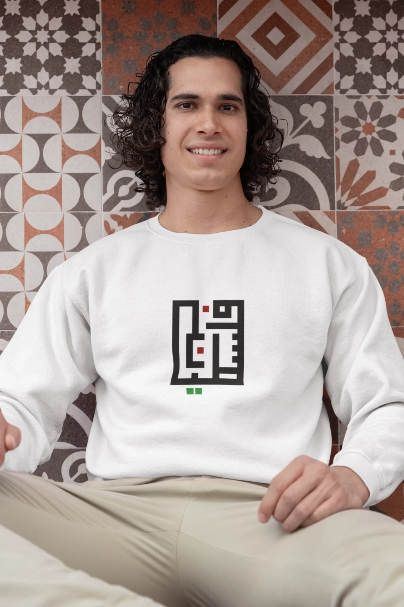 gildan-sweatshirt-mockup-of-a-man-with-curly-hair-sitting-by-a-tiled-wall-m33134